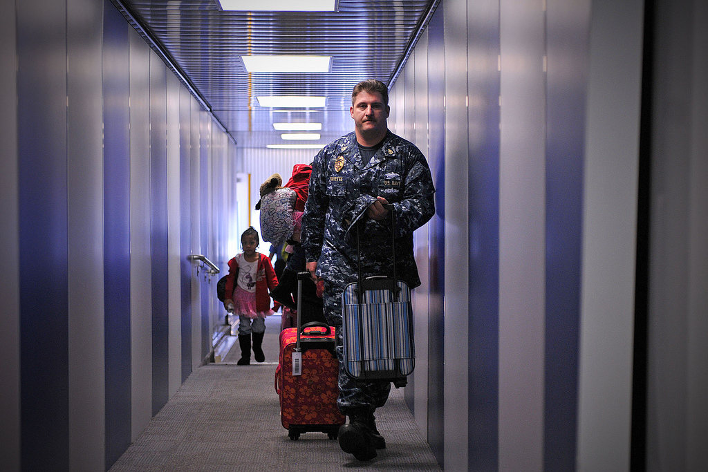 Image of Sailor carries bags for U.S. military family members arriving in Florida after evacuating Japan.